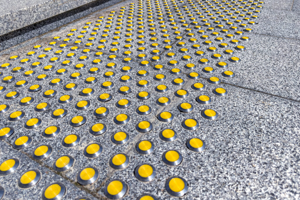 gray granite staircase with yellow tactile indicators for visually impaired people
