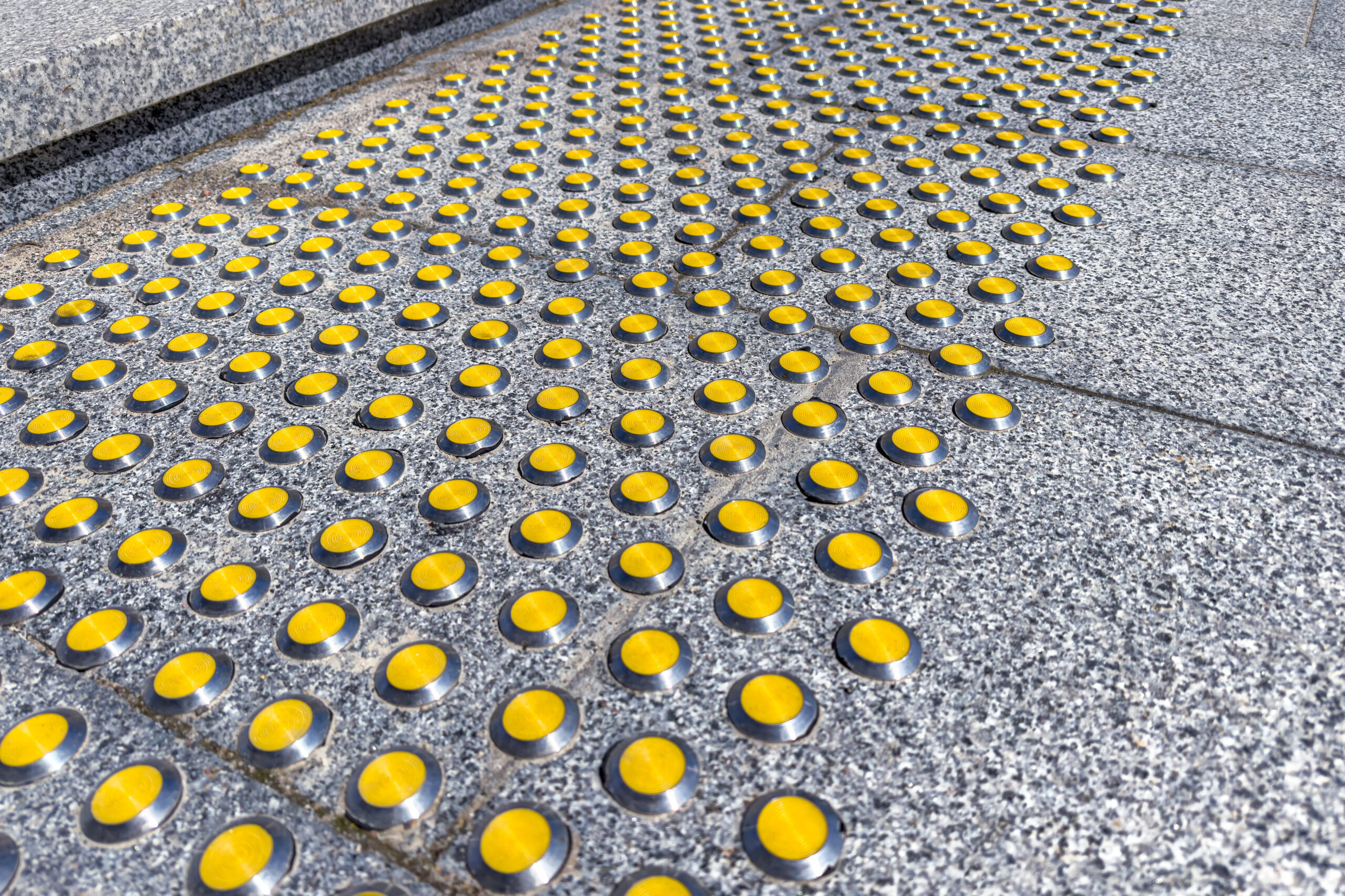 gray granite staircase with yellow tactile indicators for visually impaired people