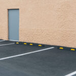 A car park with lined bays outside a building, and a door in a wall. ,Sante Fe,USA